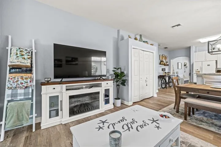 Living area featuring visible vents, arched walkways, baseboards, and wood finished floors
