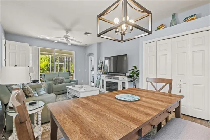 Dining space with arched walkways, visible vents, ceiling fan with notable chandelier, and light wood-type flooring
