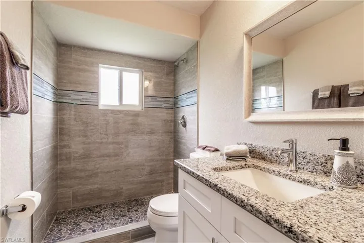 Bathroom featuring hardwood / wood-style floors, a tile shower, toilet, and vanity