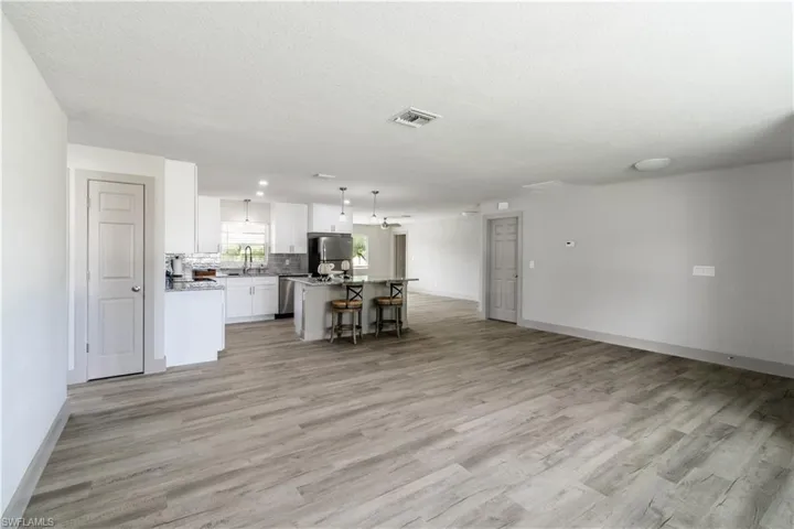 Kitchen with decorative light fixtures, a kitchen island, white cabinets, and light wood-type flooring