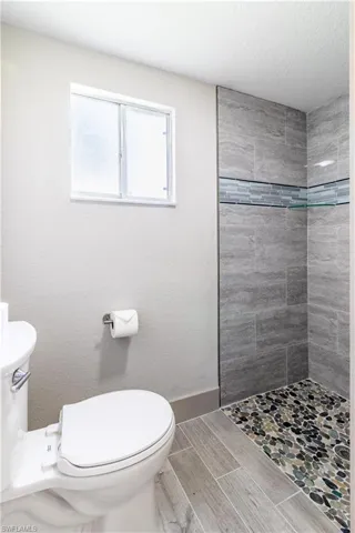 Bathroom featuring a tile shower and toilet