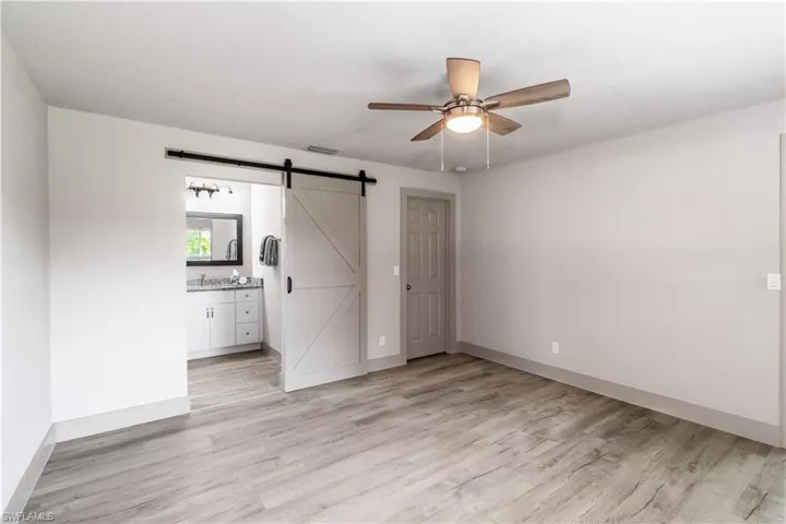 Unfurnished room featuring a barn door, light hardwood / wood-style flooring, and ceiling fan