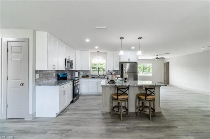 Kitchen featuring pendant lighting, a kitchen island, light hardwood / wood-style flooring, white cabinets, and appliances with stainless steel finishes