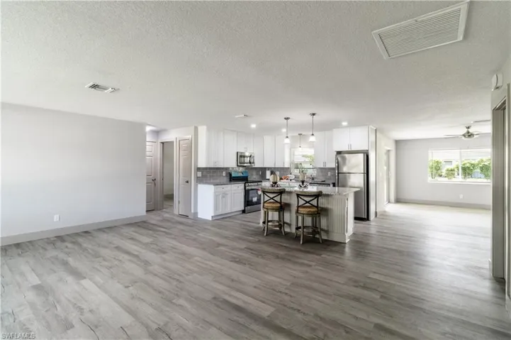 Kitchen featuring stainless steel appliances, white cabinetry, a kitchen island, and a kitchen breakfast bar