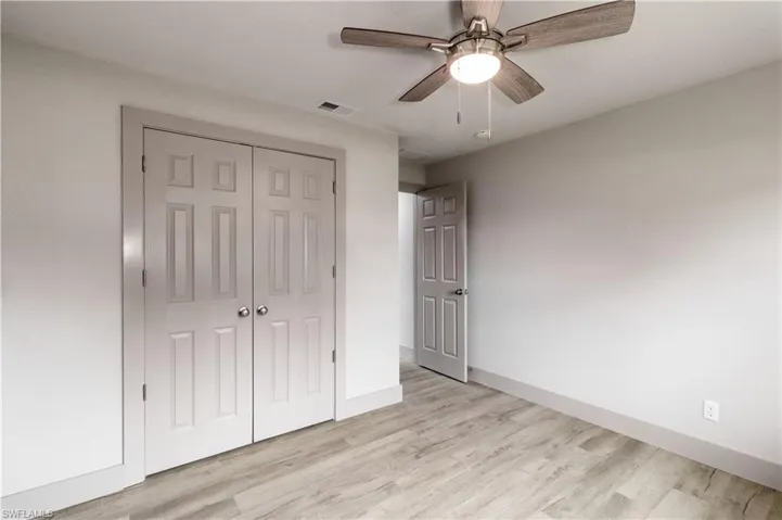 Unfurnished bedroom with a closet, light hardwood / wood-style floors, and ceiling fan