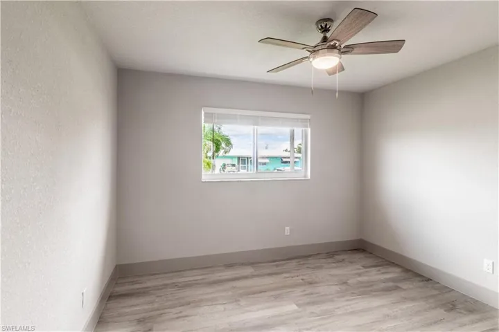 Empty room featuring a textured ceiling, light wood-type flooring, and ceiling fan