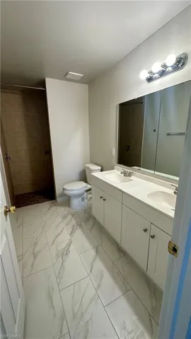 Bathroom with double vanity, marble finish flooring, and tiled shower