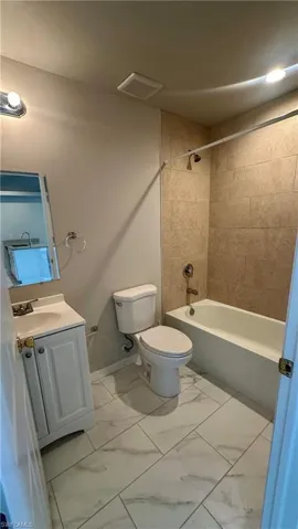 Bathroom with marble finish flooring, shower / bathtub combination, and vanity