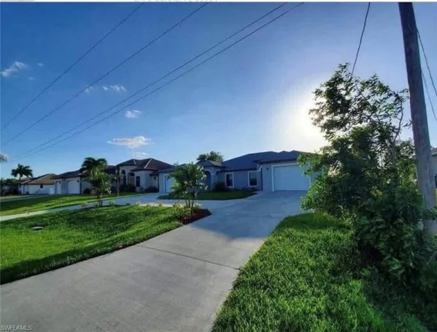 Ranch-style home featuring concrete driveway, a front lawn, an attached garage, and a residential view