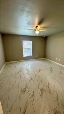 Spare room with light marble finish floors and a ceiling fan