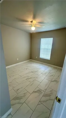 Empty room with light marble finish flooring and a ceiling fan