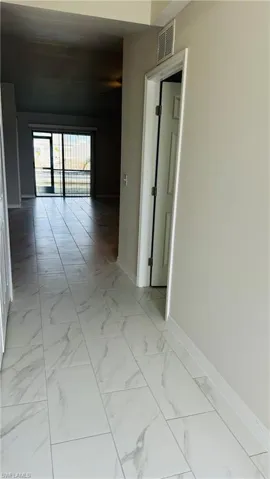 Corridor featuring light marble finish floors and baseboards