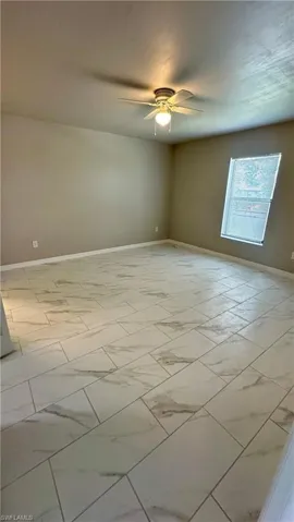 Empty room featuring light marble finish flooring and a ceiling fan