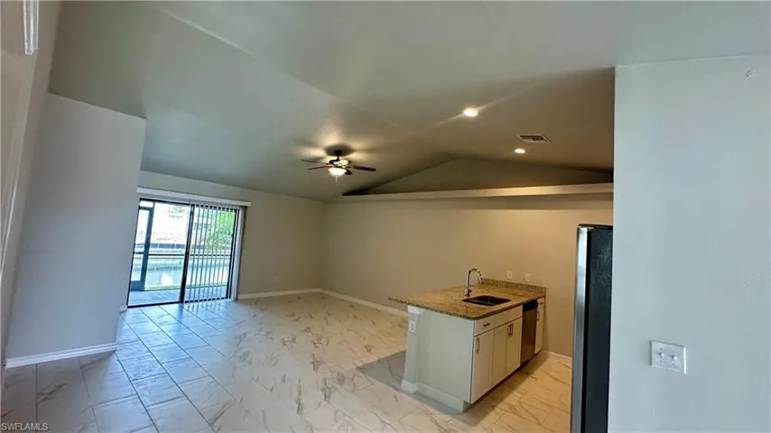 Kitchen featuring light marble finish floors, stainless steel appliances, vaulted ceiling, ceiling fan, and light stone countertops