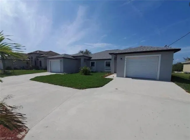 Single story home featuring concrete driveway, a garage, a front lawn, and stucco siding