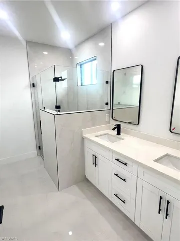 Bathroom featuring vanity, a tile shower, and tile patterned flooring