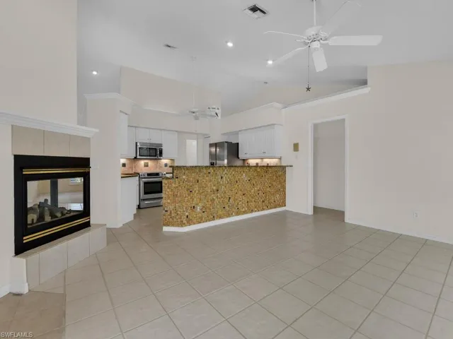 Open-concept living area featuring a tile-surround fireplace, vaulted ceilings, and tile flooring