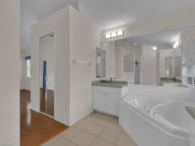 Bathroom featuring a corner soaking tub, dual vanities with integrated sinks, and tiled flooring