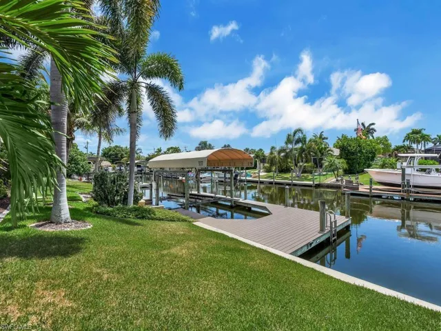 Waterfront property featuring a private boat dock with a covered lift, composite decking, and direct canal access