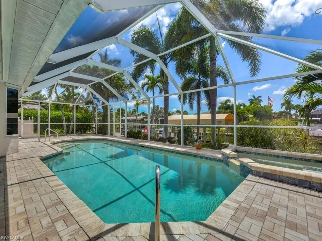 Screened outdoor pool area featuring a rectangular pool with integrated spa