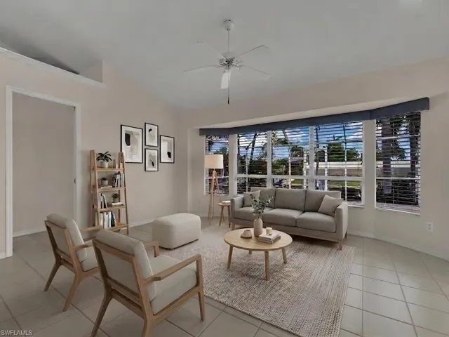 Spacious living area featuring a large bay window, tile flooring, vaulted ceilings, and a ceiling fan