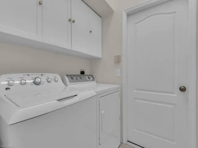 Utility area featuring white cabinetry with brushed nickel hardware, light-toned wall paint, and a painted paneled door with a round knob