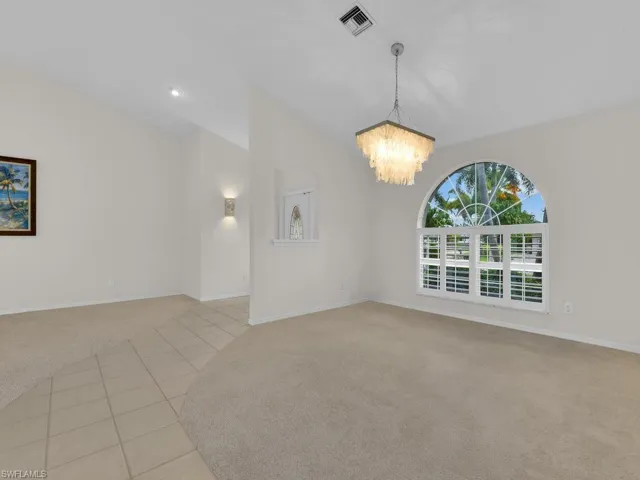 Arched window with plantation shutters, vaulted ceiling, and recessed lighting