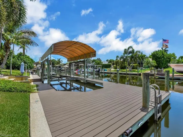 Waterfront property featuring a composite deck, boat lift with canopy, and a dock ladder