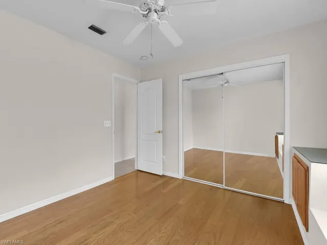 Room featuring wood-finish flooring, a ceiling fan, and white baseboards