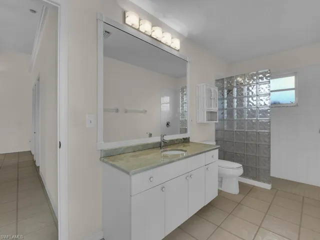Bathroom featuring a vanity with a light green countertop, integrated sink, and white cabinetry