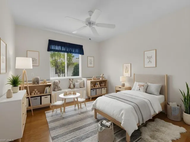 Bedroom featuring light wood-finish flooring, a window with horizontal blinds and a dark blue valance, a ceiling fan, and built-in window seating with storage