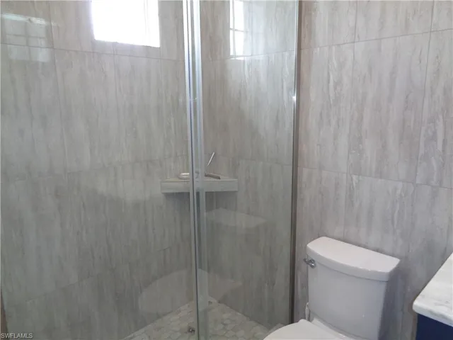 Full bathroom with a shower stall, vanity, and tile walls