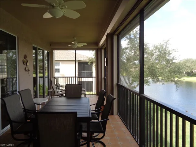 Sunroom / solarium with a water view, a ceiling fan, tile patterned floors, a balcony, and outdoor dining space