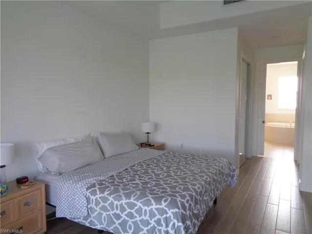 Bedroom with dark wood-style floors and ensuite bath