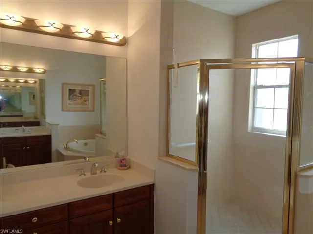 Bathroom with two vanities, a stall shower, and a garden tub