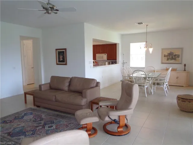 Living room featuring light tile patterned flooring, a chandelier, and ceiling fan