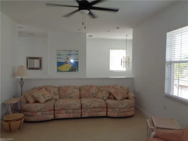 Tiled living area with ceiling fan and a chandelier