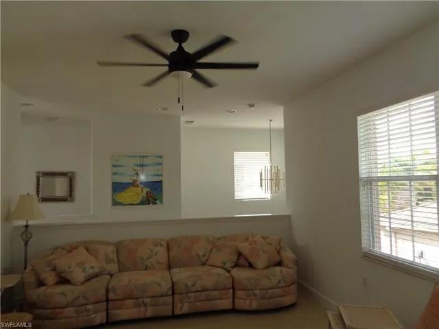 Living room with a ceiling fan, tile patterned floors, and a wall mounted AC