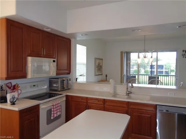 Kitchen with white appliances, healthy amount of natural light, brown cabinetry, and recessed lighting