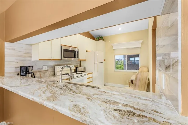 The kitchen has an extra-large pass through to the dining area and accommodates barstools, too. The neutral granite and tiled backsplash, gooseneck faucet with Stainless Steel undermount sink are fairly recent updates.