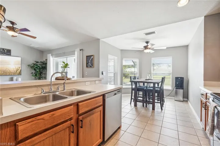 Kitchen featuring sink, ceiling fan, light tile floors, and stainless steel appliances