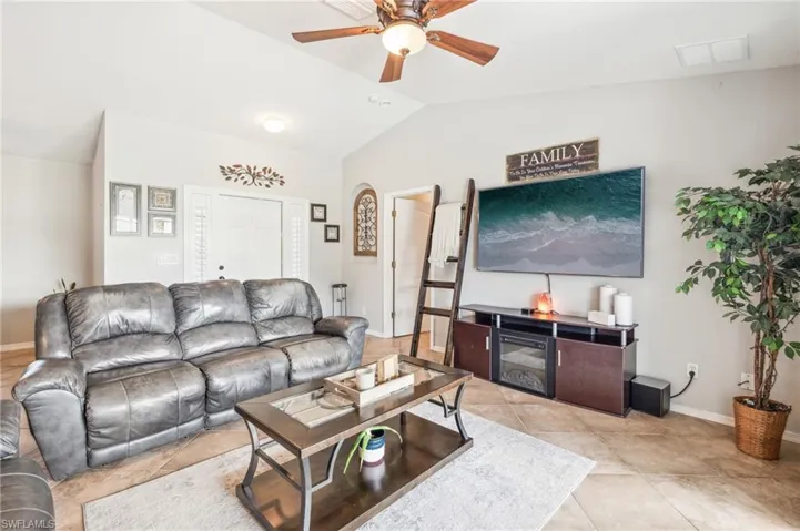 Living room featuring vaulted ceiling, ceiling fan, and light tile floors