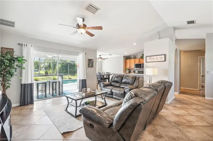 Tiled living room featuring lofted ceiling and ceiling fan