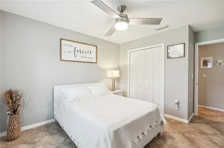 Tiled bedroom with ceiling fan and a closet
