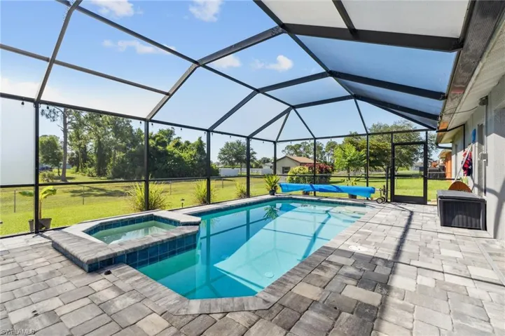 View of pool with a lawn, a lanai, an in ground hot tub, and a patio