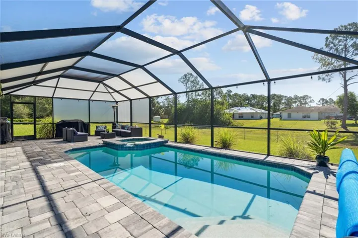 View of swimming pool featuring a patio, a lanai, an in ground hot tub, and a lawn