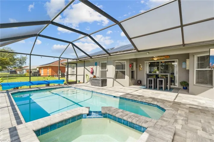 View of pool with ceiling fan, an in ground hot tub, glass enclosure, and a patio area