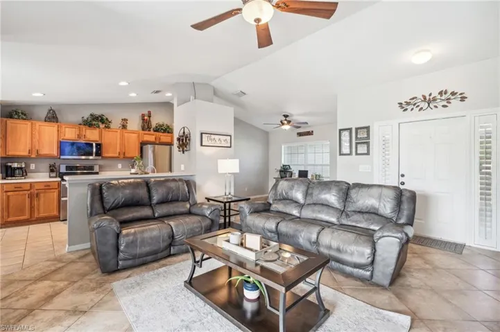 Living room featuring light tile floors, ceiling fan, and vaulted ceiling