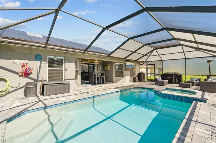View of swimming pool with a patio area, glass enclosure, an in ground hot tub, and grilling area
