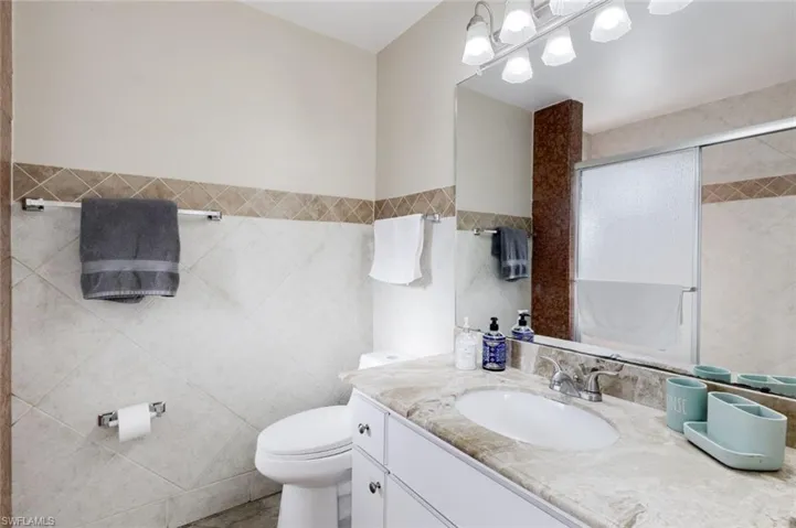 Full bath with vanity, a shower stall, and tile walls